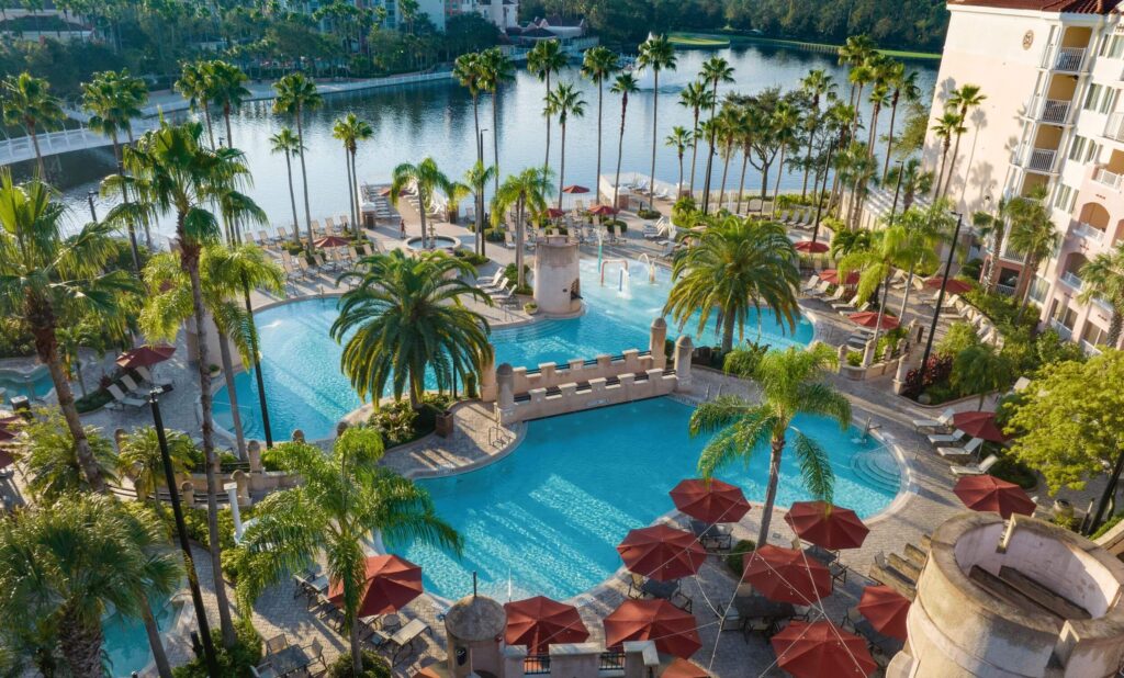 several organic shaped pools surrounded by palm trees and red umbrellas